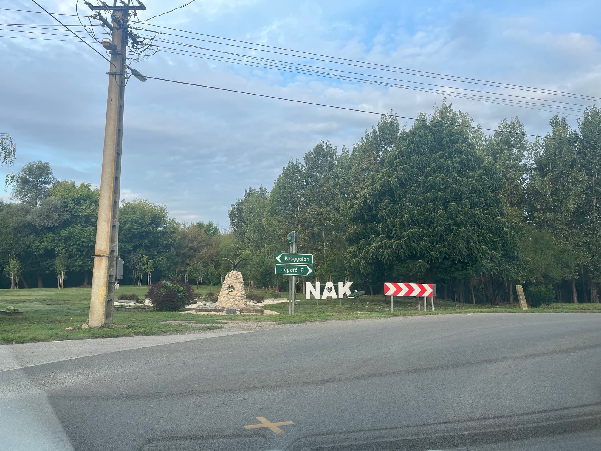 Dorpsbord NAK bij het kruispunt tussen bomen